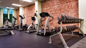 A gym with treadmills, ellipticals, and a dumbbell rack.