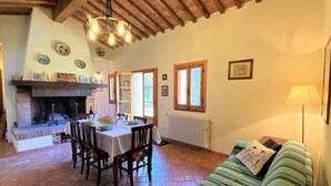 Una sala de estar acogedora con chimenea, comedor y un sofá con lámpara.