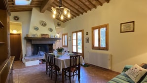 Un comedor acogedor con chimenea, techo de madera y una mesa preparada para cuatro.