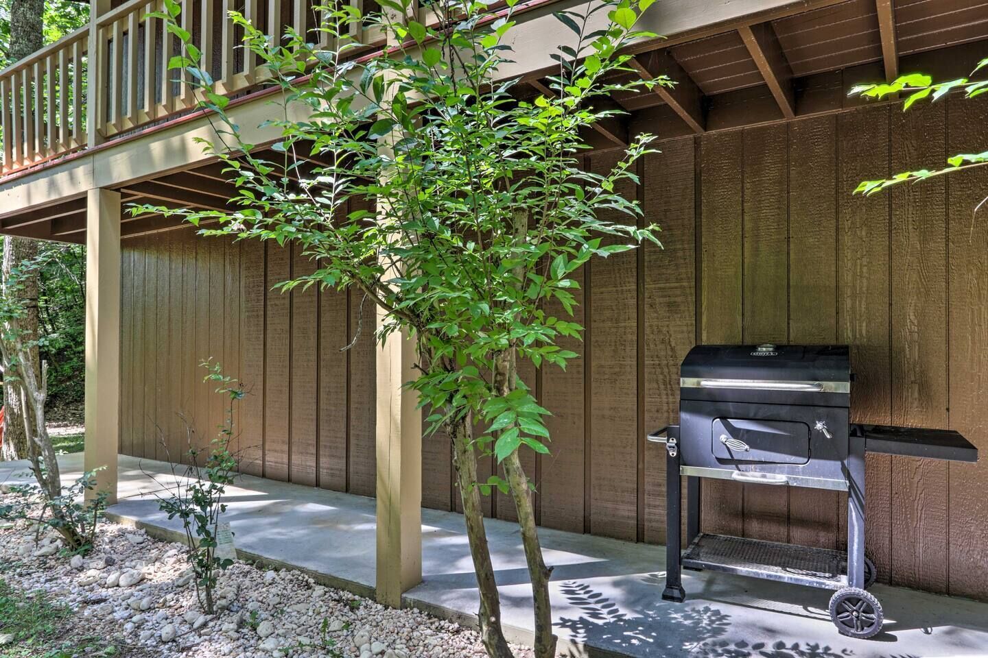 A wooden deck with a barbecue grill, surrounded by a wooden fence and small trees.