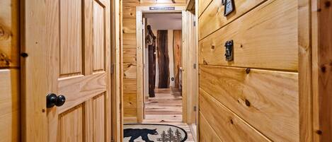 A wooden hallway with a bear rug at the end, wooden walls, and a sign that reads "Want to wake the bear?"