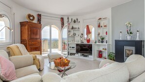 A spacious living room with a large window, a fireplace, and a well-organized bookshelf.