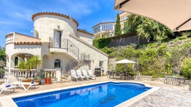A poolside area with a swimming pool, lounge chairs, and a dining table.
