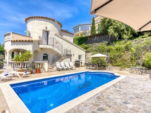 Un espace aménagé au bord de la piscine, comprenant une piscine, des chaises longues et une table à manger.