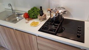 A kitchen with a stainless steel sink, a stove, and a countertop with a plate of spaghetti, a bottle of olive oil, a wooden spoon, and a bunch of green lettuce. - Beautiful private villa for 6 guests with pool, A/C, WIFI, TV and terrace (Umag)