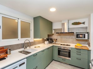 A modern kitchen with a sink, stove, microwave, and cabinets.