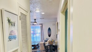 A hallway with wooden flooring, a dining area with a table and chairs, and a ceiling fan. - Surfside Serenity at Bidawee PCB (Panama City Beach)