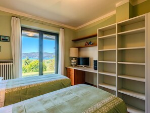 A bedroom with two beds, a TV, and a shelf with decorative items.