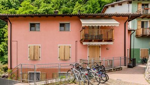 En bygning med rosa facade, træpersienner og en balkon med gelænder.