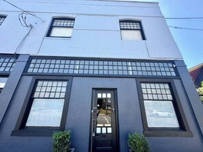 A building with a dark facade, large windows, and a visible door.
