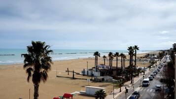 Une route bordée de palmiers, avec des installations de plage, et offrant une vue sur l’océan.