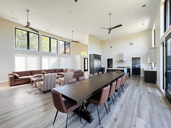 Amplia sala de estar con una gran mesa de comedor, un sofá y una zona de cocina con electrodomésticos modernos.