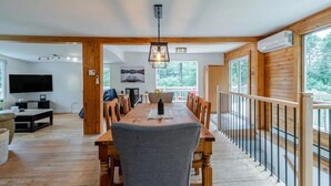 Ett rymligt matområde med ett långt träbord, stolar och en hängande lampa.