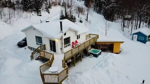 Ett snötäckt hus med en veranda och ett bubbelbad.