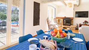 Un coin repas avec une table dressée pour deux personnes, une cheminée et un téléviseur fixé au mur.