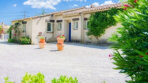 Un bâtiment de style rustique, avec un toit en tuiles, une allée en gravier et des plantes en pot.