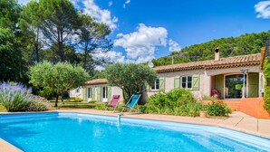 Une piscine à l’eau d’un bleu cristallin, entourée d’un jardin où poussent différentes espèces de plantes et d’arbres.