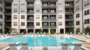 Um edifício moderno com apartamentos, piscina central, várias varandas e áreas de estar ao ar livre.