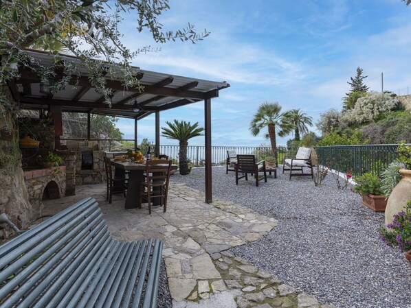 An outdoor patio with stone flooring, a pergola, and seating.