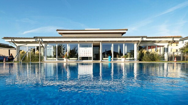 A swimming pool with a clear view of a building in the background. - Nice apartment for 2 people with pool, WIFI, TV and terrace (Grevesmühlen)