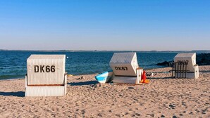 A beach with three white beach chairs labeled DK66, DK67, and DK67. - Nice apartment for 2 people with pool, WIFI, TV and terrace (Grevesmühlen)