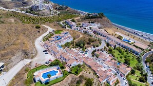 An aerial view of a coastal residential area with terraced houses, a swimming pool, and a beach. - Beautiful apartment for 4 guests with WIFI, pool, A/C, TV, terrace and pets allowed (Torrox)