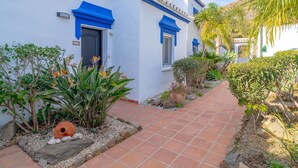 A white building with blue trim and a tiled pathway leading to a door marked with the number 619. - Beautiful apartment for 4 guests with WIFI, pool, A/C, TV, terrace and pets allowed (Torrox)