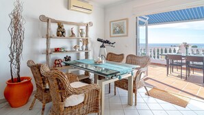 A room with a glass table, wicker chairs, a telescope, and a view of the sea. - Beautiful apartment for 4 guests with WIFI, pool, A/C, TV, terrace and pets allowed (Torrox)