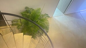 Um interior moderno com escada, planta em vaso e luminária.