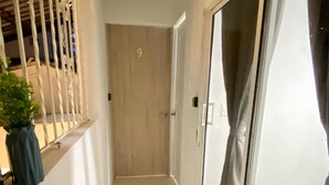 Um corredor com uma porta de madeira, uma porta de correr de vidro e um vaso com planta.