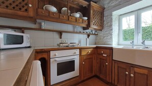 Une cuisine avec des meubles de rangement en bois, un four à micro-ondes et une cuisinière.