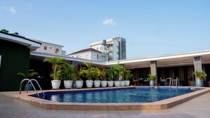 A swimming pool with potted plants, outdoor seating, and a building in the background. - Presken Hotel Residence  (Lagos)