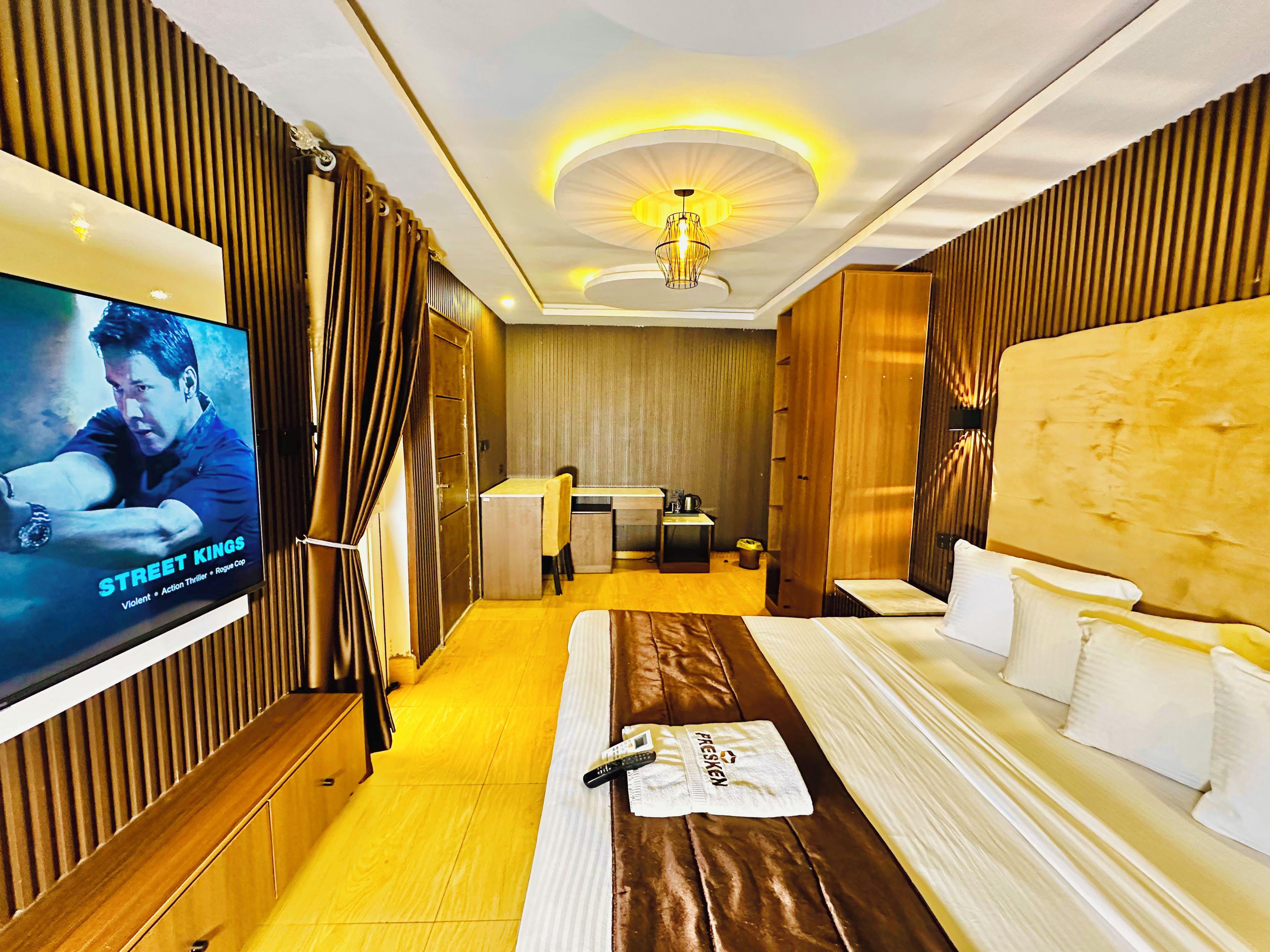 A hotel room with a bed, a desk, a television, and a bathroom.