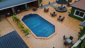 Una piscina rectangular con solárium empedrado, rodeada de mobiliario exterior y plantas en macetas.