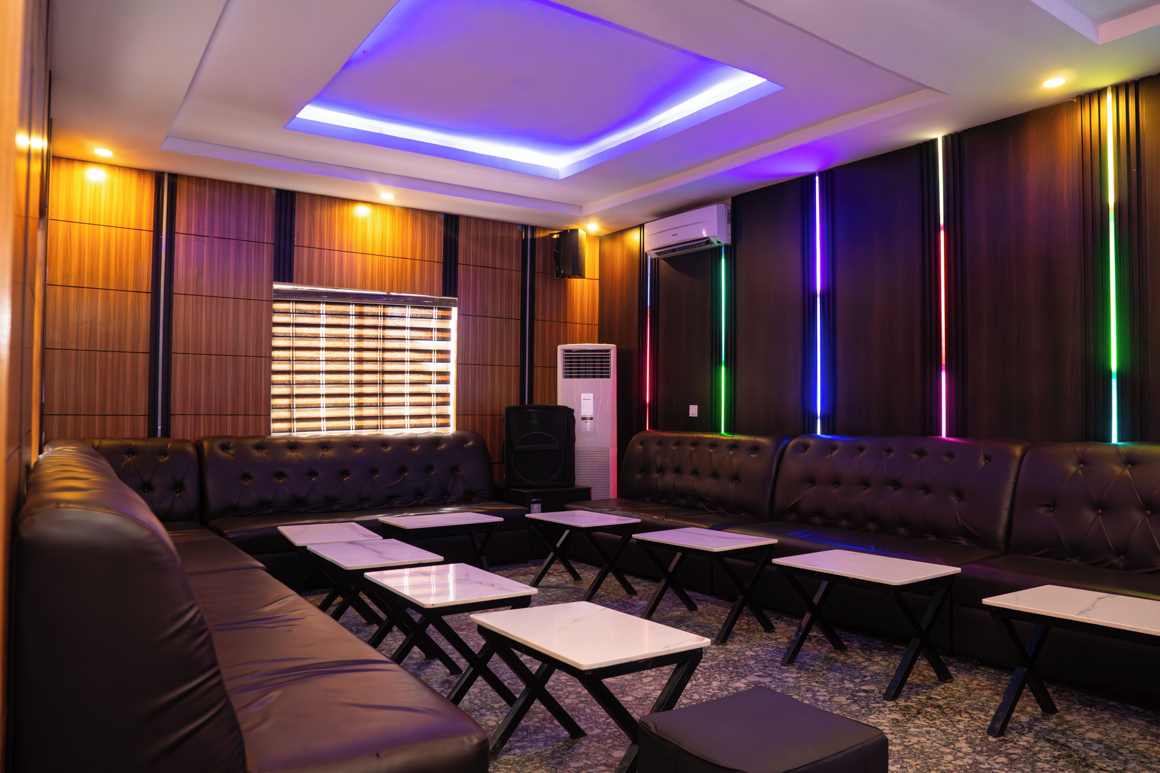 Um lounge moderno com sofás de couro, mesas e um teto com iluminação em LED.
