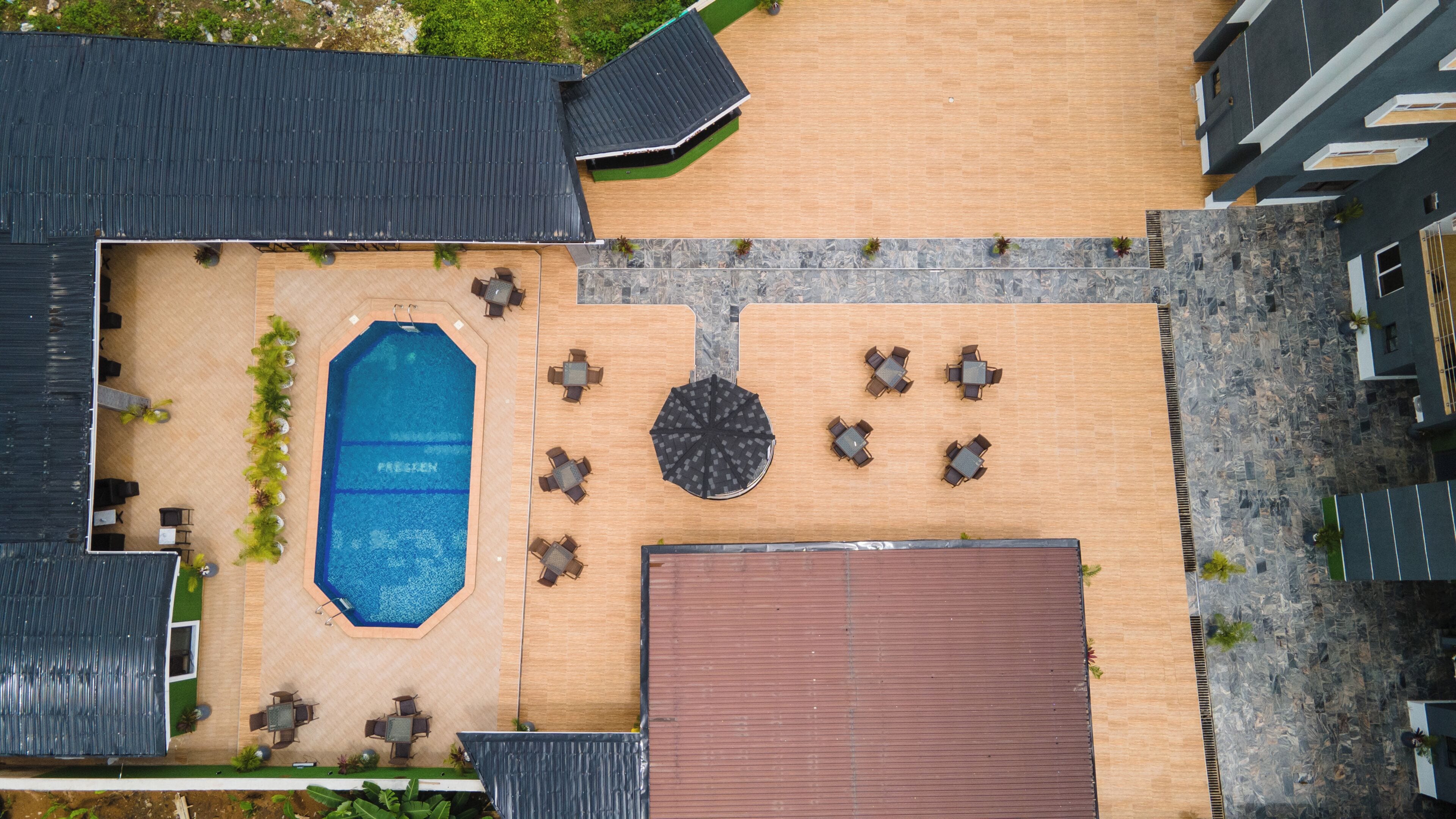 Vista aérea de un hotel con piscina, mobiliario exterior y una zona cubierta.