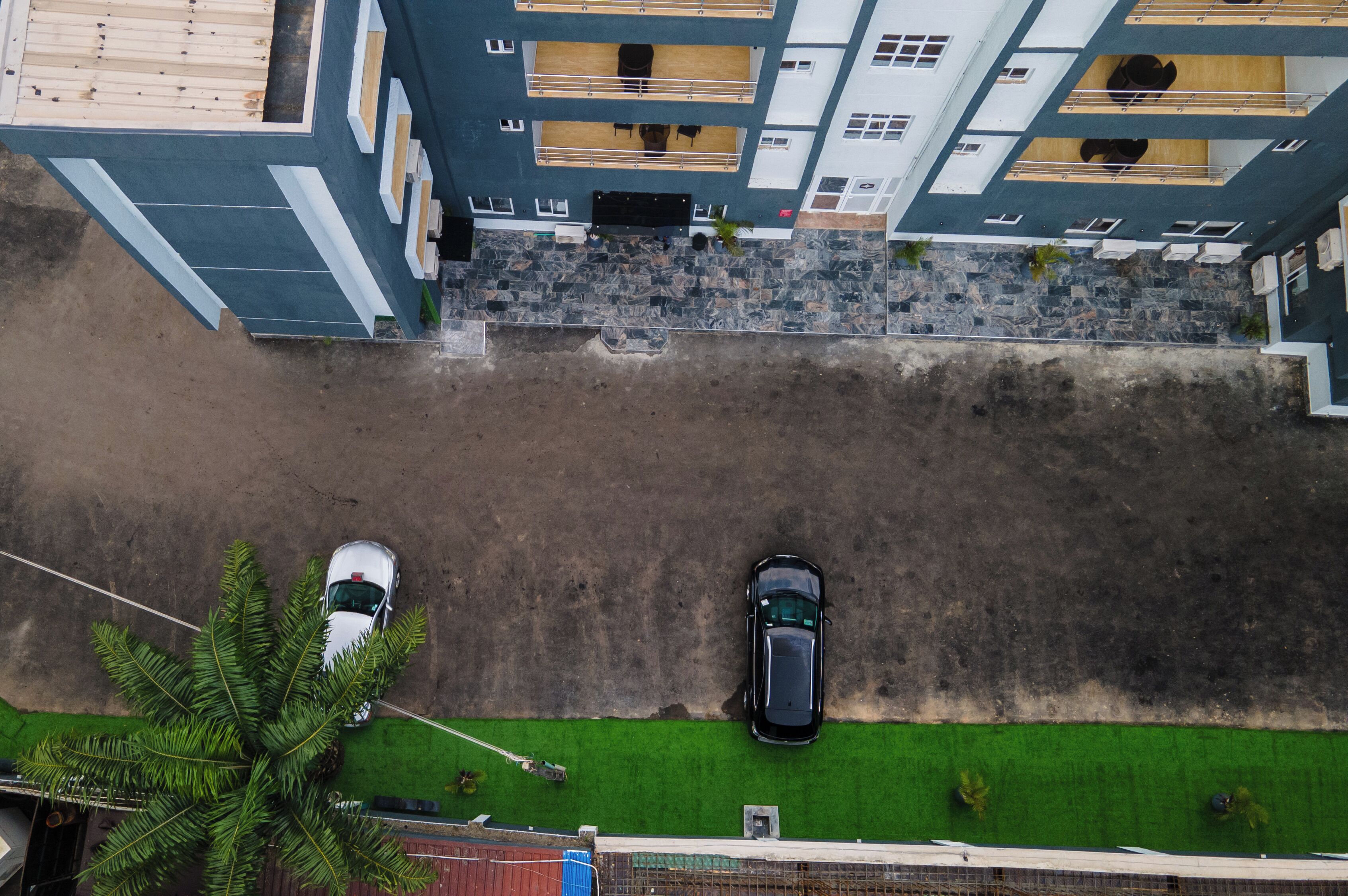 An aerial view of a building with a parking area, two cars, and a green lawn.