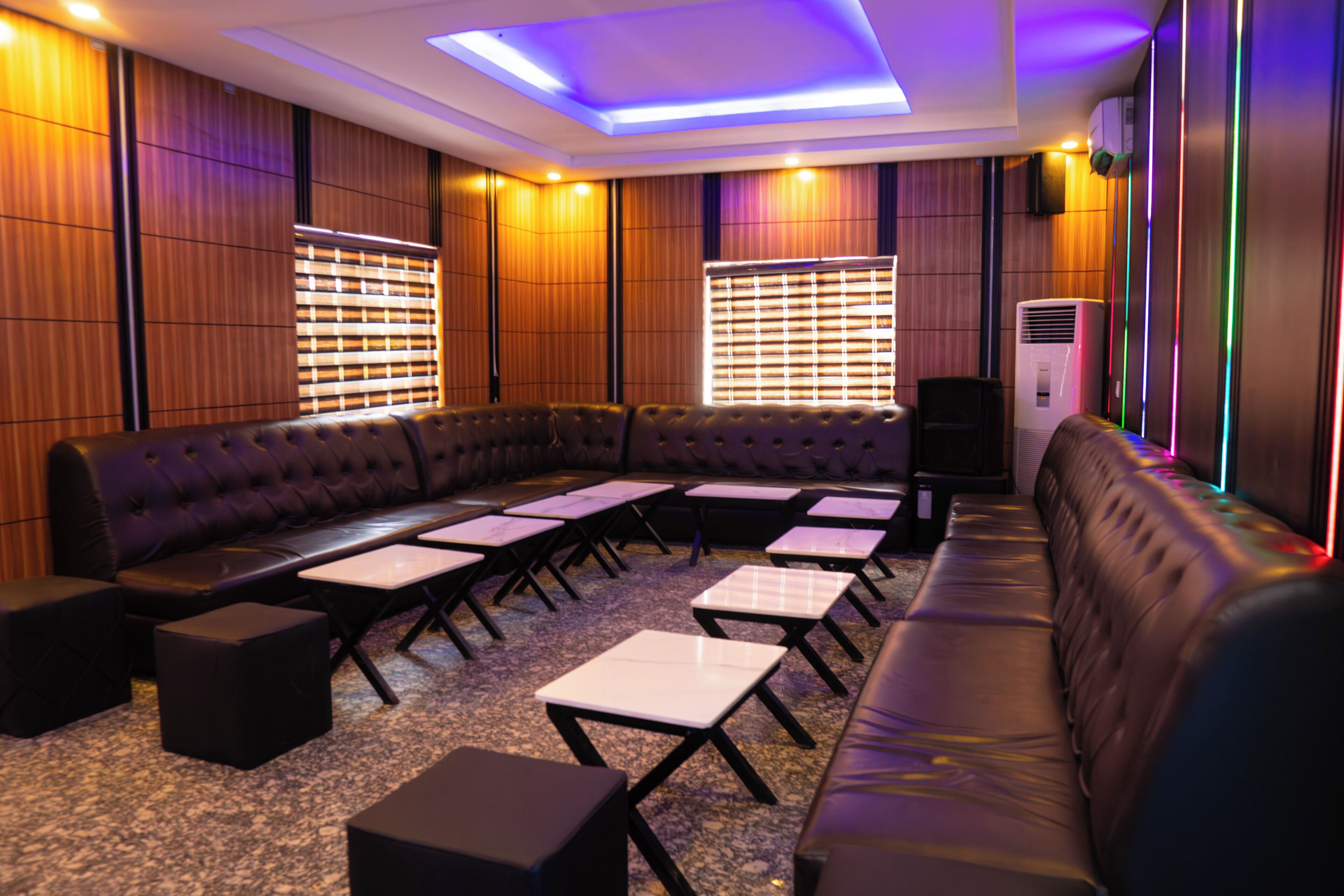 A modern lounge area with a curved leather sofa, small tables, and a ceiling light fixture.