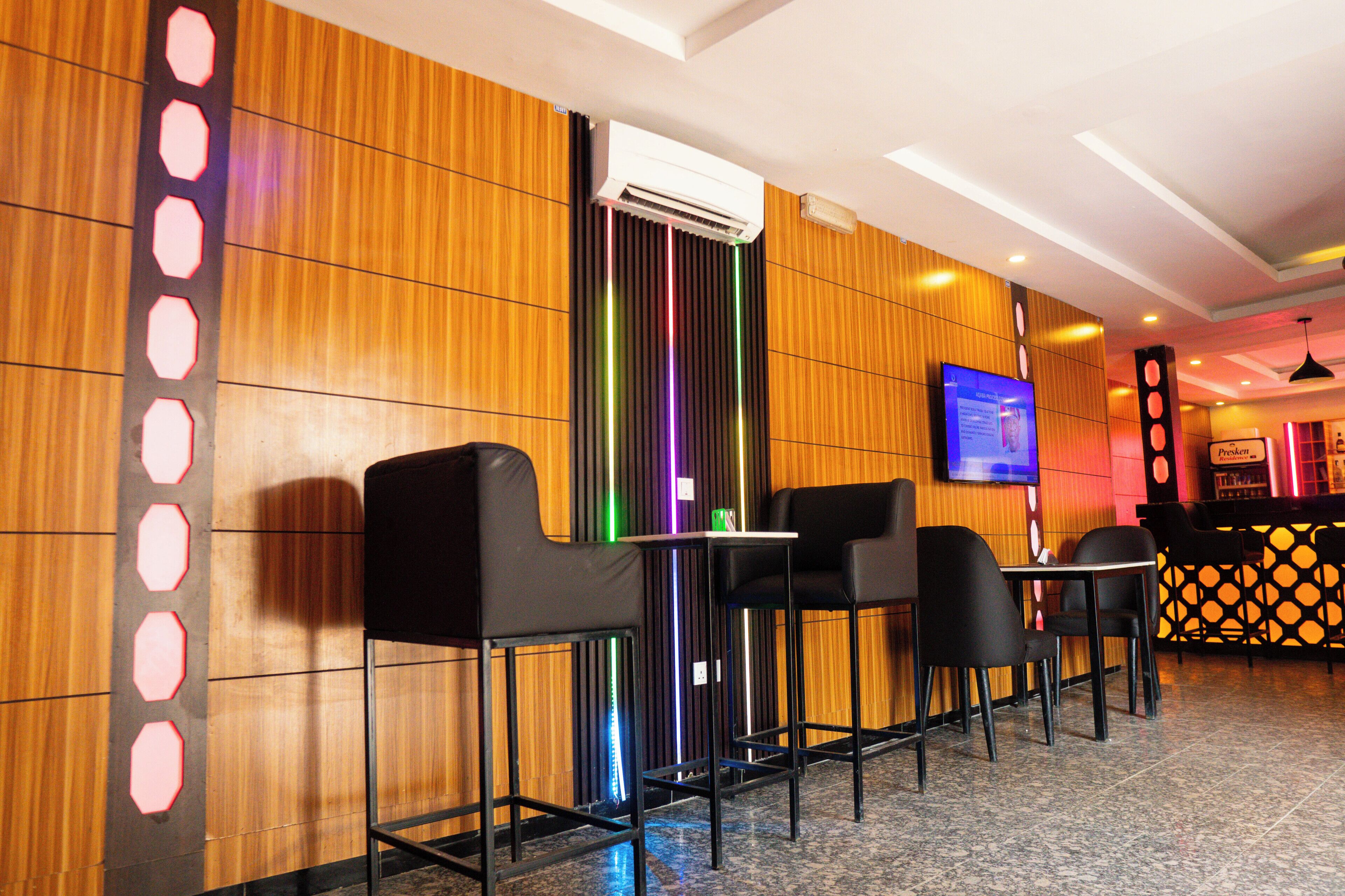 Un moderno vestíbulo de hotel con paneles de madera, una televisión de pantalla plana y asientos de bar.