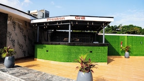 Un restaurante llamado 'Fresken Grill' con una pared de césped artificial verde y un techo negro.