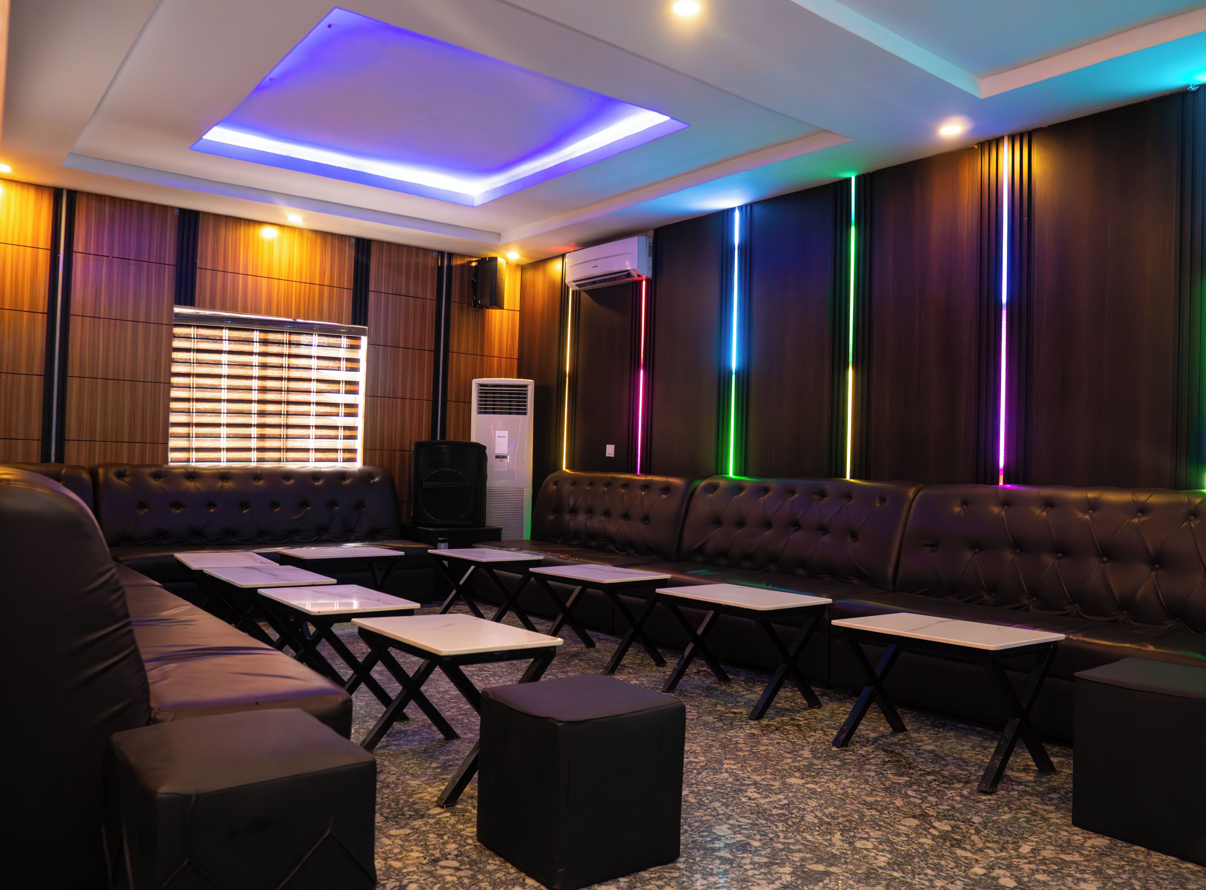 A room with a sofa, tables, and a ceiling with LED lights.