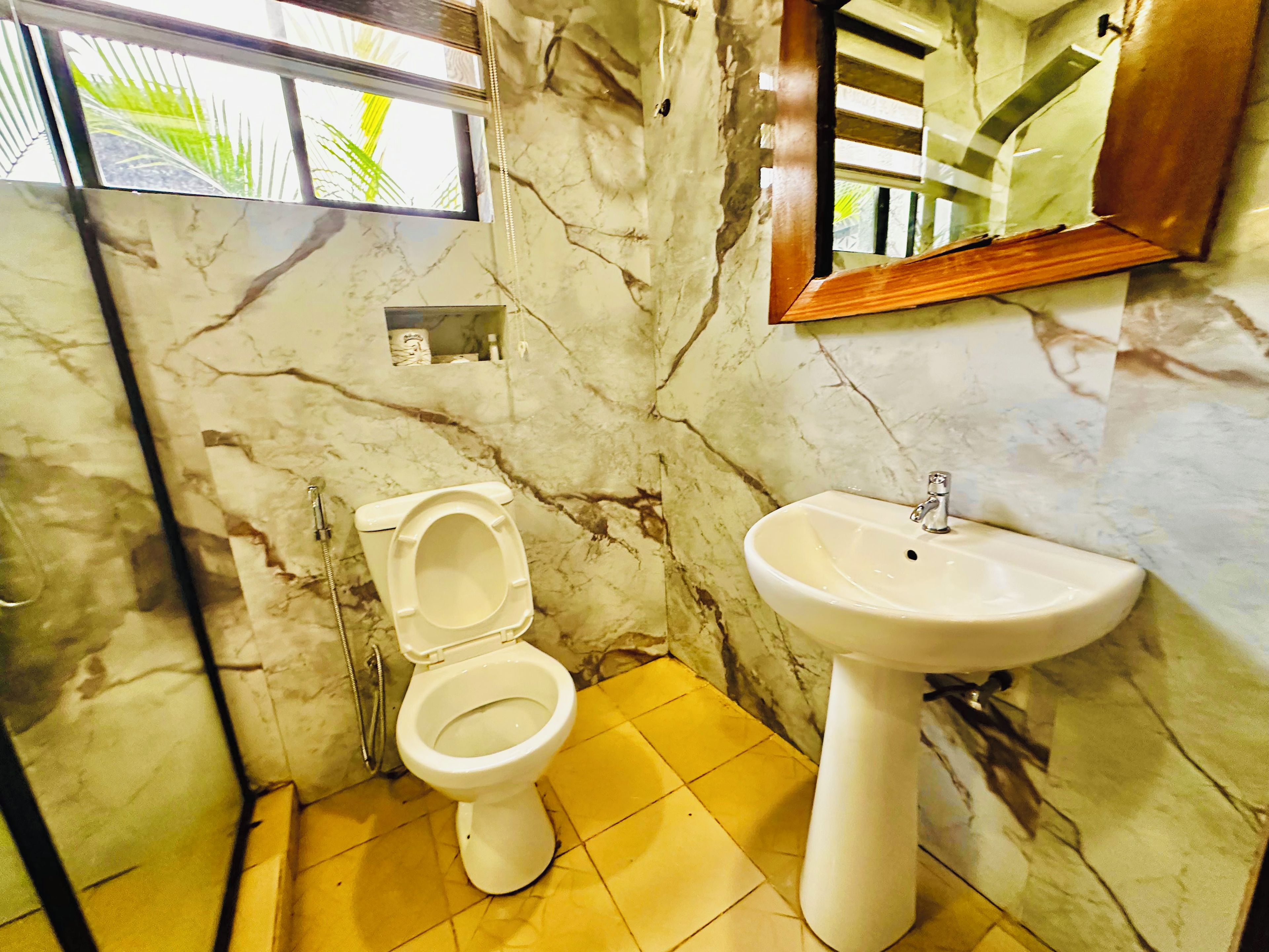 A bathroom with a toilet, sink, and marble walls.