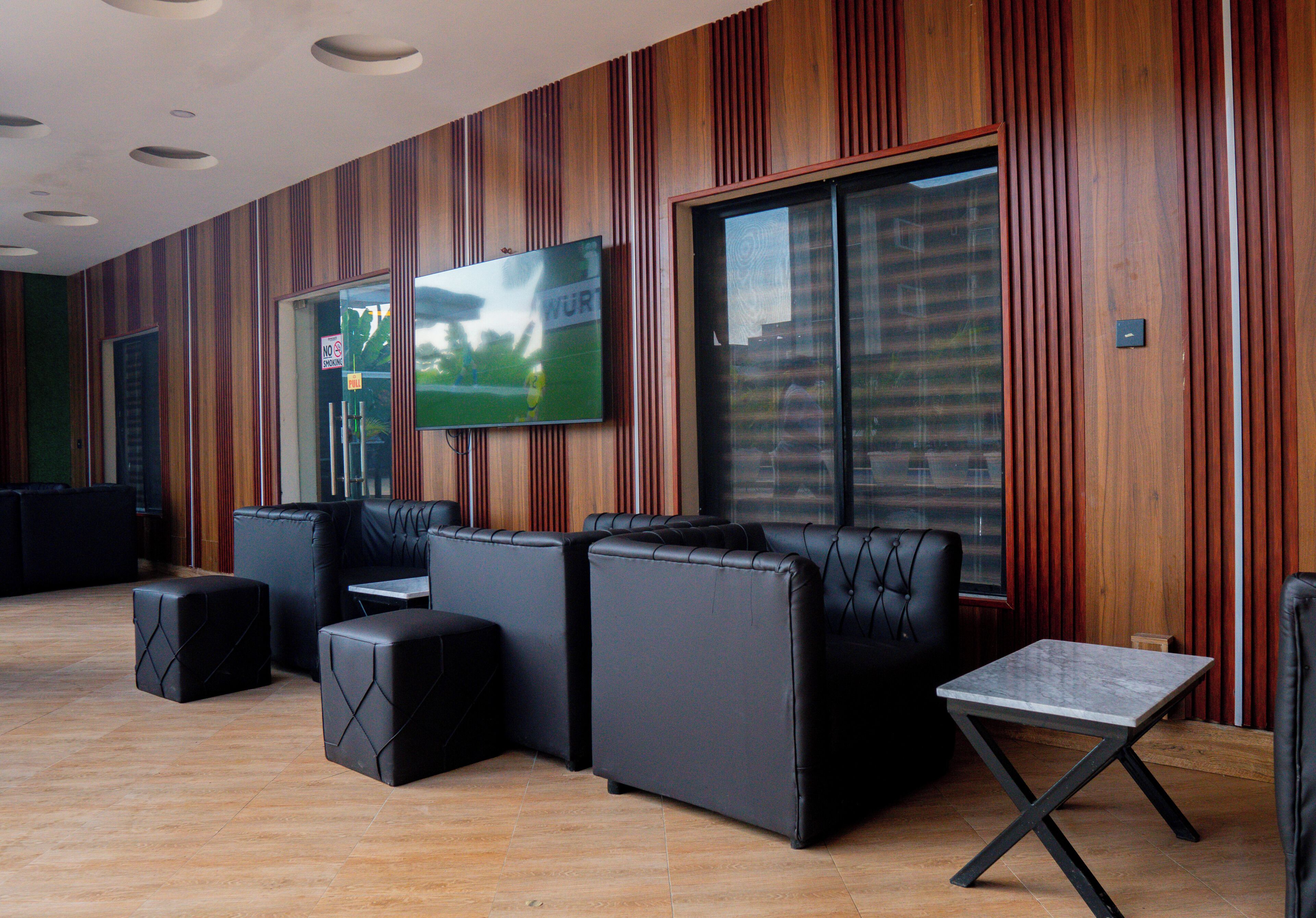 A modern lounge area with leather sofas, a small table, and a television mounted on the wall.