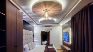 A modern hotel room with a large bed, a television, and a ceiling light fixture. - Presken Hotel Residence  (Lagos)