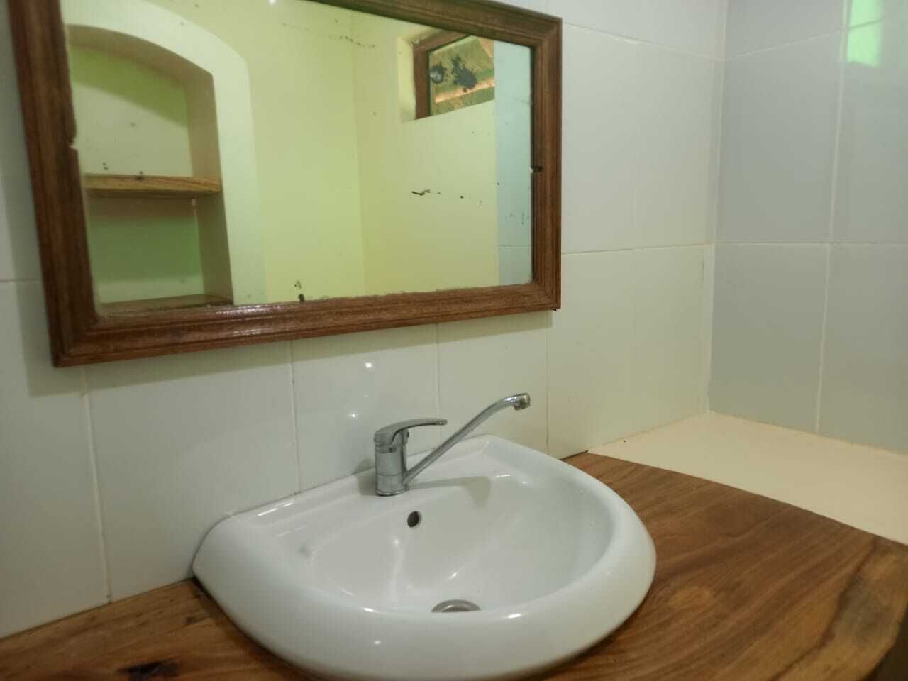 A bathroom with a white sink, a wooden vanity, and a mirror with a wooden frame.