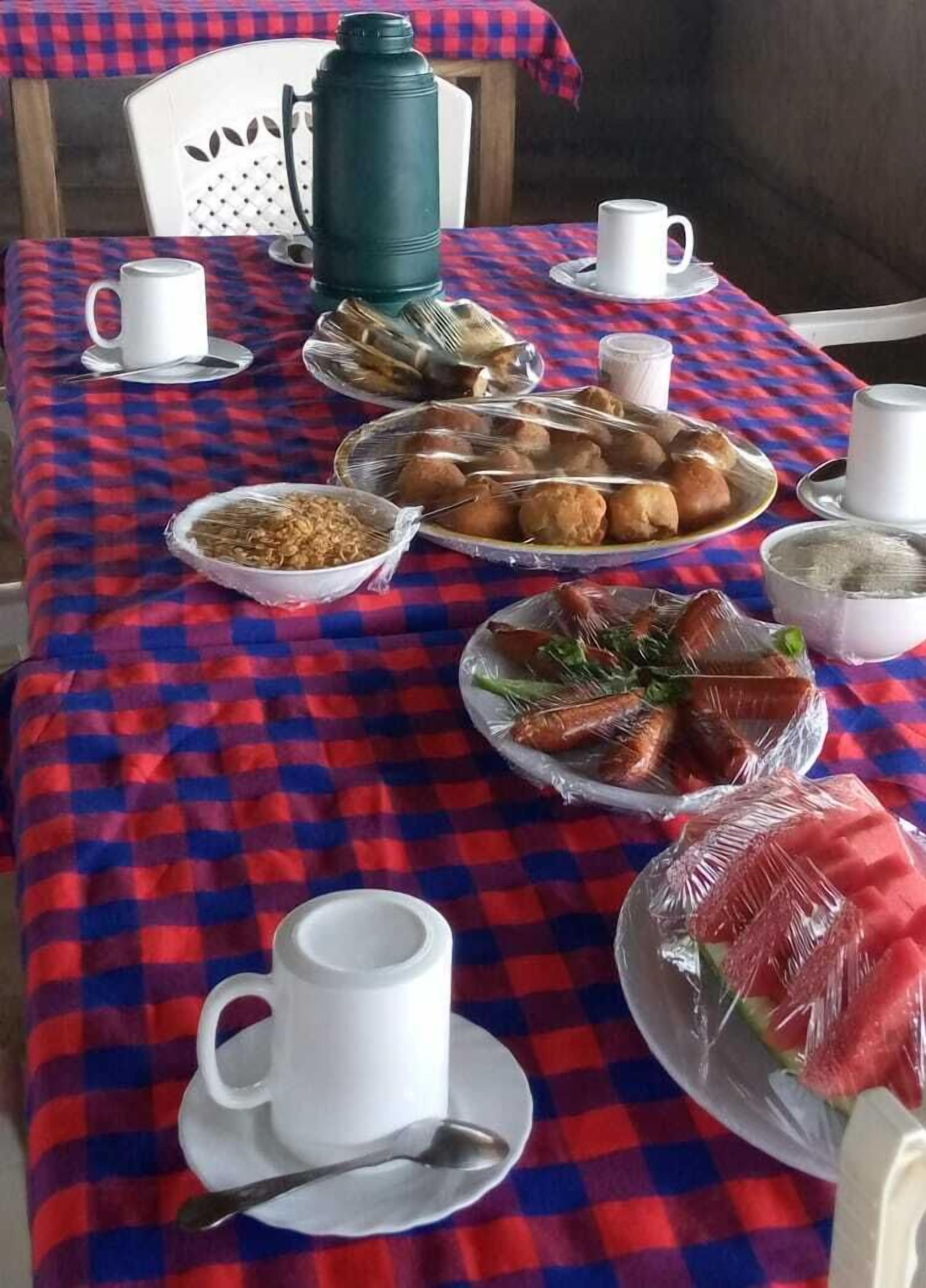 Una mesa dispuesta con varios platos, incluyendo pan, verduras y un bol de cereales, sobre un mantel a cuadros.