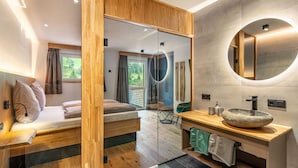 Un baño moderno con tocador de madera, espejo redondo y lavabo de piedra.