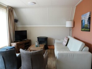 Una sala de estar con televisor, chimenea, sofá y lámpara.