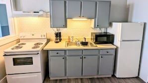 Une cuisine compacte équipée d’une cuisinière, d’un four à micro-ondes, d’un évier et d’un réfrigérateur.