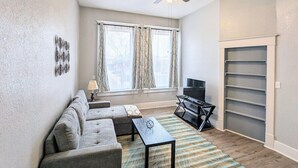 Un salon comprenant un canapé, une table basse, un téléviseur et une étagère.